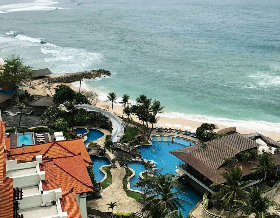 Vista aérea de un hotel con piscinas junto a la playa